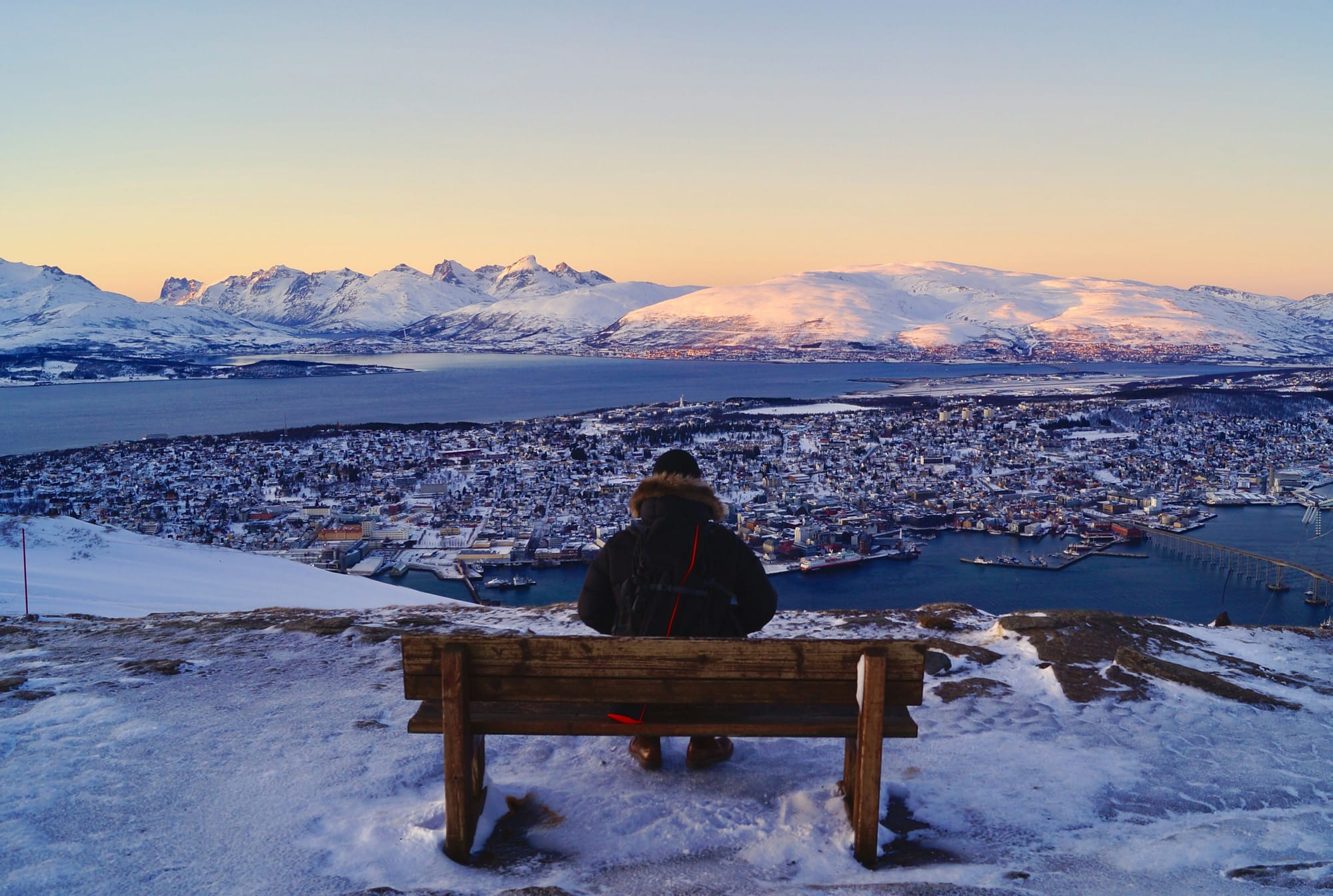 A person in the snow looks down from a mountain at Tromso, Norway, in winter